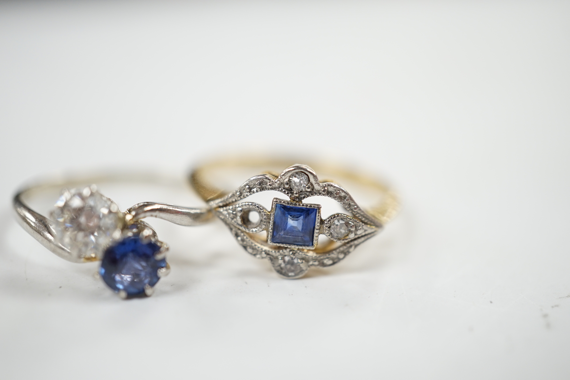 An early 20th century 18ct and plat, sapphire and diamond set cluster ring (stone missing), size N/O and a white metal, sapphire and diamond set two stone crossover ring, size M, gross weight 4.6 grams.